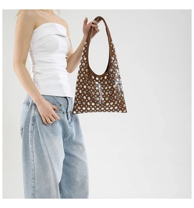 Detail of a brown leather hobo bag featuring polished silver rivets and smooth texture