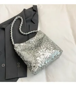 Detail of silver sequined bucket bag with woven strap on a grey blazer background