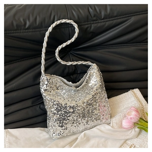 Detail of silver sequin bucket bag with braided shoulder strap on black leather backdrop