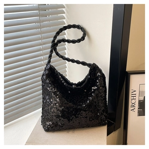 Detail of black sequined crescent bag with woven knot strap and textured finish