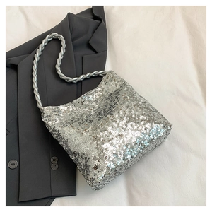 Close-up of a silver sequin tote bag with unique twisted rope handles on grey blazer
