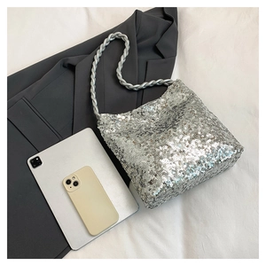 Detailed view of silver sequin shoulder bag with thick twisted rope strap on a flat lay
