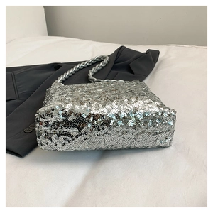 Close-up of sparkling silver sequin bucket bag with thick link chain and metallic texture