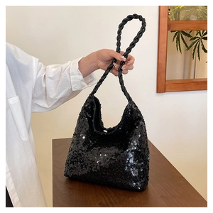 Detailed macro view of black sequined handbag with woven rope handle on wooden table