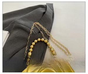 Detailed macro view of the golden metal chain strap with elegant gold circular beads
