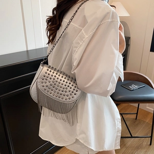 Sac bandoulière argenté à rivets et franges porté par un modèle style punk chic