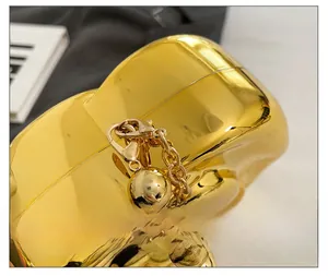 Detail view of heart-shaped gold clutch with metallic chain and spherical hardware detail