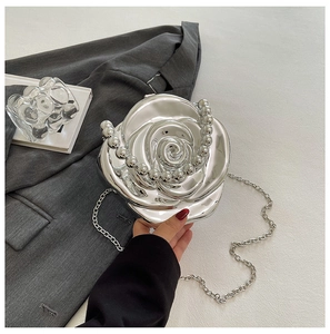 Close-up of a silver rose-shaped evening bag with a pearl handle and chain strap