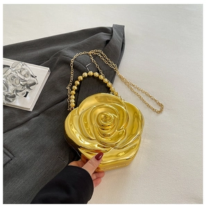 Detail of a 3D gold rose clutch with mirror finish, pearl handle, and chain strap
