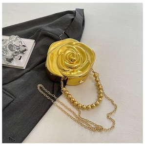 Detail of rose-shaped gold evening bag with metallic finish and beaded handle