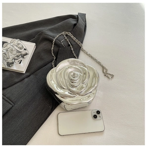 Close-up of 3D silver rose acrylic handbag with metallic mirror finish on grey blazer