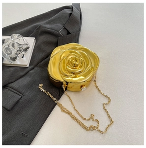 Detail of a gold rose-shaped hard shell evening clutch with a pearl clasp and chain strap