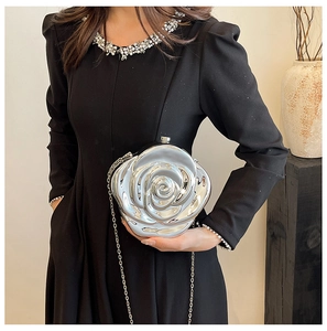 Silver rose-shaped clutch bag with metallic petals and chain worn with an evening dress