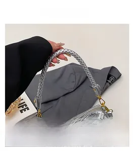 Detail of silver woven bucket bag featuring thick handles and gold hardware on grey suit