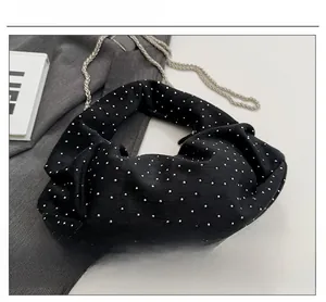Close-up of black suede hobo bag featuring silver rivets and metal chain strap