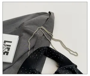 Detail of silver metal braided chain strap on a dark grey pleated handbag with polka dots