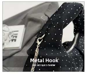 Close-up of durable silver metal lobster hook and chain on black pleated handbag