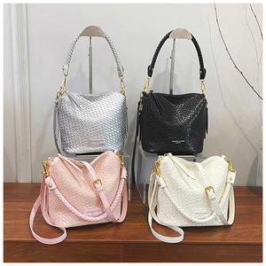 Detail of woven bucket bags in silver, black, pink, and white with golden hardware