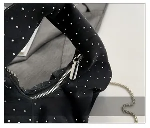 Detail of black suede dumpling bag with silver micro-rivet accents and smooth metal zipper
