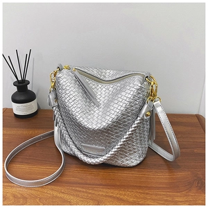 Detail view of metallic silver woven hobo bag with gold hardware and shoulder strap