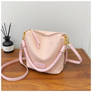 Detailed view of pink woven texture bucket bag with gold hardware and fashion brand label