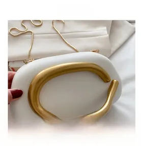 Detalle del bolso de mano nube en PU blanco con asa dorada y cadena de serpiente