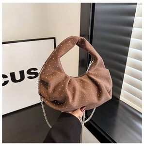 Brown suede croissant bag with silver studs and chain strap in hand-held close-up