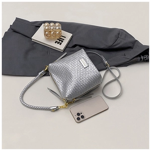 Detail of silver woven bucket bag with metallic texture and dual shoulder straps