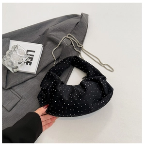 Close-up of black pleated dumpling bag with white polka dots and silver chain strap