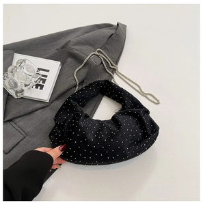 Detail of black pleated cloud bag with white pearl dots and silver metal chain strap