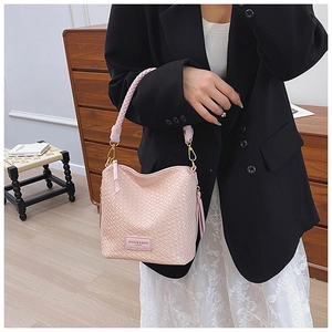 Close-up of light pink woven leather handbag with textured strap and golden hardware