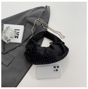 Detail of black polka dot dumpling bag featuring matte texture and silver chain strap