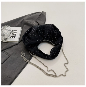 Detail of black polka dot pleated moon bag with silver chain strap and zipper closure