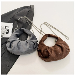 Detailed view of pleated polka dot half-moon bags in blue and brown with silver chains