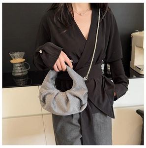 Gray pleated moon bag with white dot accents and chain strap shown in a lifestyle setting