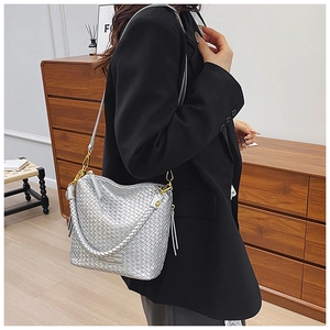 Detail of silver woven bucket bag featuring gold hardware and elegant side tassels