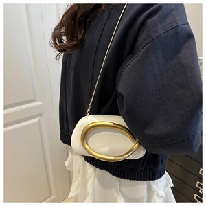 Detalle de bolso de cuero PU blanco con asa metálica dorada en forma de C y correa de cadena