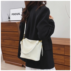 Detailed view of a white woven bucket bag with gold hardware and stylish handle