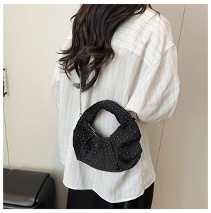 Macro detail of black pleated polka dot dumpling bag with silver chain strap and handle