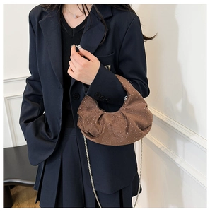 Close-up of brown suede moon bag with sparkling studs and elegant silver chain strap
