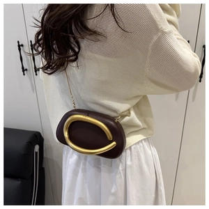 Detalle de bolso bandolera de cuero PU marrón oscuro con adorno metálico en forma de C dorado