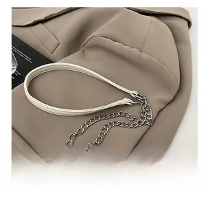 Détail de la bandoulière en cuir blanc et chaîne argentée sur fond de veste kaki