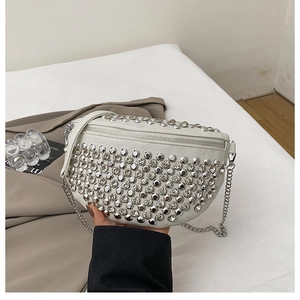 Gros plan sur un sac demi-lune blanc orné de rivets argentés et d'une chaîne métal