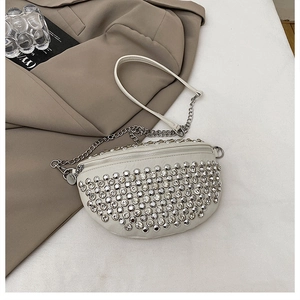 Détail du sac demi-lune blanc orné de clous argentés et de strass sur le cuir
