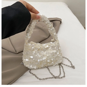 Macro detail of shimmering white sequins and silver chain strap on the cloud bag
