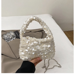 Close-up of white sequin handbag with round sequins and silver metal chain strap