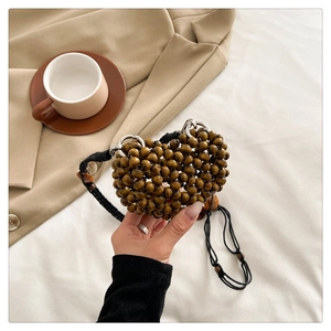 Detail of heart-shaped hand-woven wooden bead bag with a long black crossbody strap
