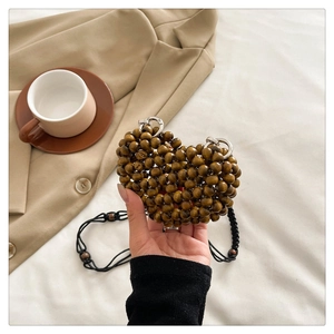 Detail of handcrafted brown wooden beads on heart shaped woven mini shoulder bag