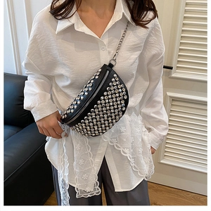 Détail du sac bandoulière noir orné de strass porté sur une chemise blanche
