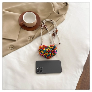 Detail of colorful heart-shaped beaded mini bag with off-white cotton rope strap